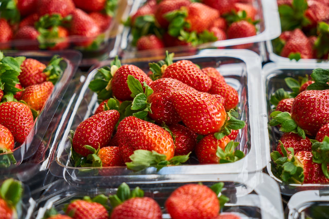 Close-up of bright red strawberries in plastic containers, showcasing freshness and vibrant color.